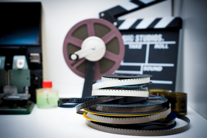 A vintage 8mm movie editing desktop with reels and clapper
